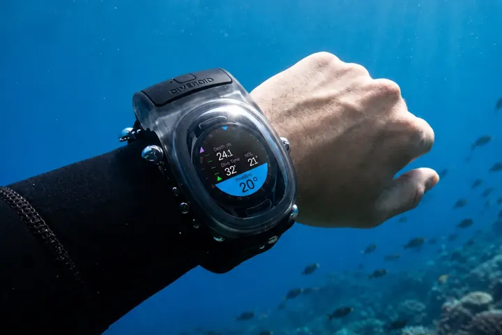 WatchDive on a diver’s wrist over a coral reef, showing depth and dive time